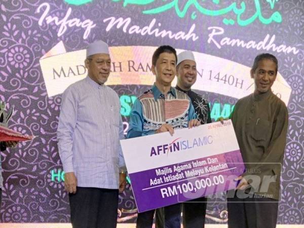 Ahmad (kiri) menyaksikan penyampaian zakat daripada Affin Islamic kepada Majlis Agama Islam dan Adat Istiadat Negeri Kelantan yang diwakili Timbalan Yang Dipertuanya, Dr Nik Azlan Abd Hadi (kanan) bernilai RM100,000.