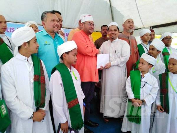 Mujahid (dua dari kiri) menyampaikan sumbangan kepada pihak pengurusan Pondok Tahfiz Padang Bongor di Tanah Merah di sini hari ini.