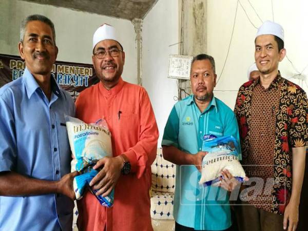 Mujahid (dua,kiri) menyampaikan sumbangan beras kepada penduduk pada Program Menteri Bersama Rakyat di Pondok Raudhatul Ulum, Kampung Serendah, Chetok.