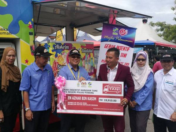 Ishak (tiga dari kiri) menyampaikan replika cek geran insentif karavan tani kepada Azhar sempena lawatan kerjanya di Penang FAMA Fest 2019, pagi tadi.