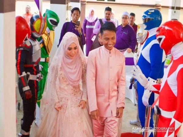 Zul Azlan Zulkepli (kanan) dan pasangannya, Nur Wahida Ahmad Razali, berjalan masuk menuju ke pentas sambil diiringi adiwira bagi acara memotong kek.