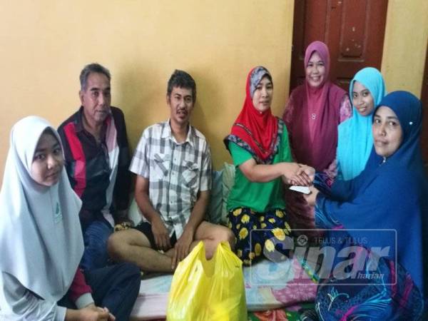 Suriyani (empat, kanan) menerima sumbangan dari Faizah di rumahnya di Kampung Telok Kerang, kelmarin. Turut hadir, ketua kampung, Tahir (dua, kiri).