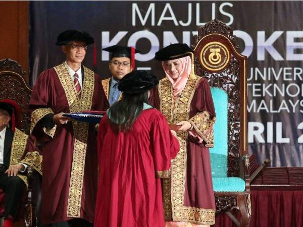 Raja Zarith (kanan) menyampaikan ijazah kepada salah seorang penerima semasa majlis konvokesyen berkenaan.