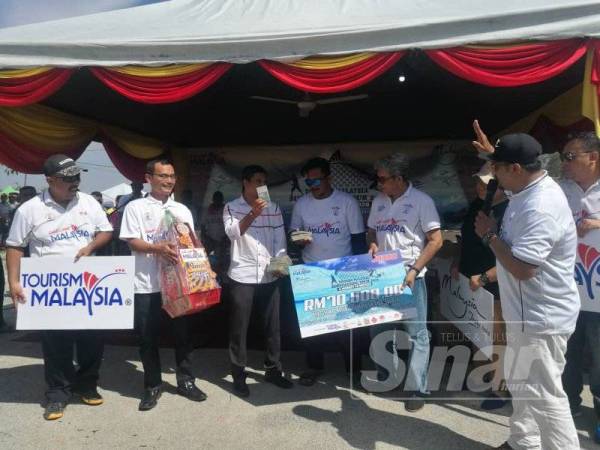 Mat Yasin (tiga dari kanan) menerima wang tunai RM70,000 yang disampaikan oleh Mohd Shaid (tiga dari kiri) di Pantai Remis, semalam.