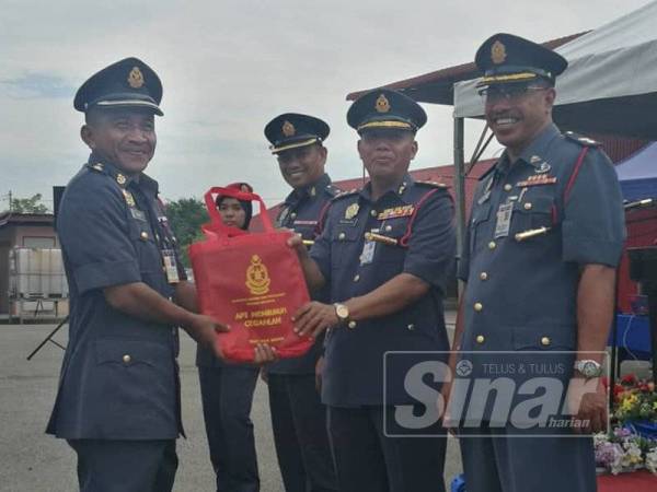 Md Salleh (dua dari kanan) diiringi Yus Heary dan Anwar (kanan) menyampaikan peralatan khas kepada Ketua Balai Bomba dan Penyelamat Pasir Puteh, Azhar Elmi Mustofar.