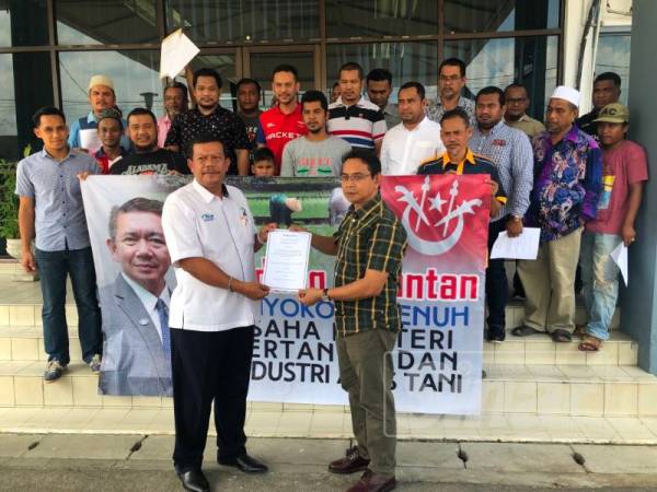 Wan Mohd Rozman Wan Mamat (kanan) menyerahkan memorandum sokongan kepada wakil Pengarah PPN Kelantan di Pejabat PPN negeri di Lundang, hari ini.