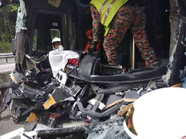 Anggota bomba melakukan kerja-kerja mengeluarkan mayat pemandu bas yang tersepit. FOTO- IHSAN BOMBA