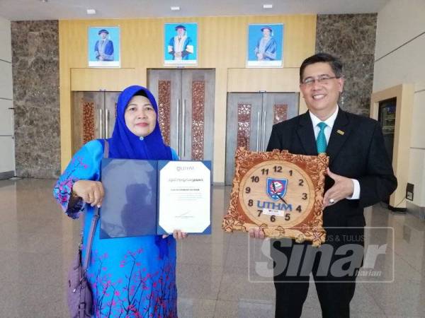 Zawiah (kiri) bersama Naim menunjukkan penghargaan yang diterima daripada UTHM.