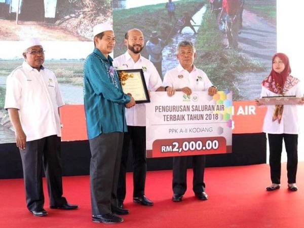 Mukhriz (tiga dari kanan) menyampaikan anugerah pengurusan saluran air terbaik 2018 kepada wakil PPK A-II Kodiang pada majlis itu. - Foto: Facebook Mukhriz Mahathir FC