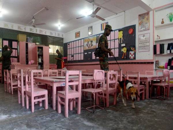 Anggota unit pemusnah bom Sri Lanka menggunakan anjing pengesan ketika memeriksa sebuah sekolah di Colombo, semalam. - Foto AFP