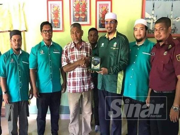 Nurul Amin (tiga, kanan) menyerahkan anugerah tokoh wira muda negara bagi menghargai pengorbanan Muhammad Adib, kepada Mohd Kassim (tiga, kiri) di rumah keluarga di Kampung Tebengau Tepi Laut, Kuala Kedah.