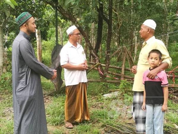 Abd Nasir (tengah) meninjau keadaan di belakang rumah Ahmad.