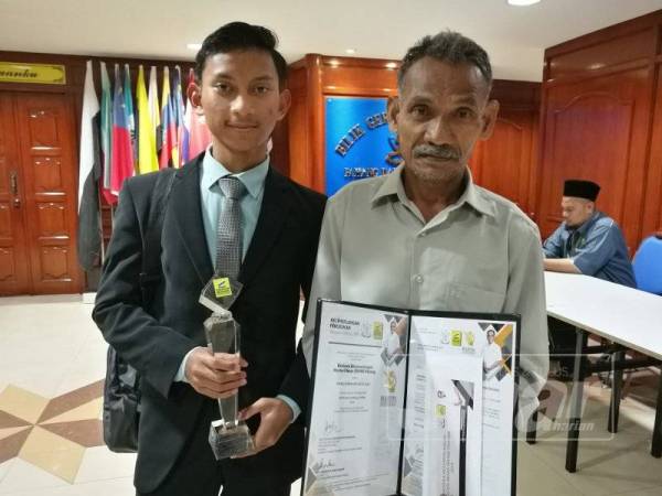 Abdul Manaf bersama ayahnya, Abdul Aziz Osman, 60 menunjukkan sijil penghargaan, serta plugue sempena menerima BKMB di Wisma Pahang di sini hari ini.