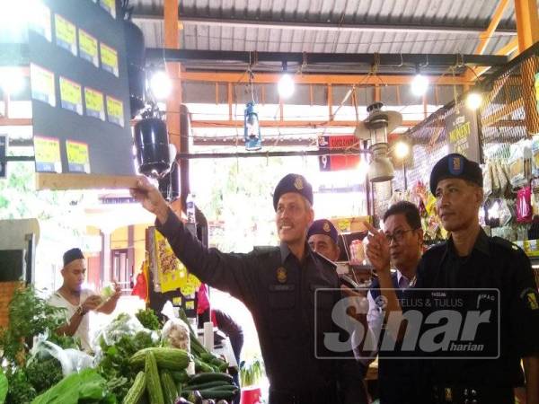 Muhammad Aizudin melihat tanda harga di sebuah permis menjual sayur-sayuran ketika pemeriksaan di Pasar Alor Gajah di sini hari ini.