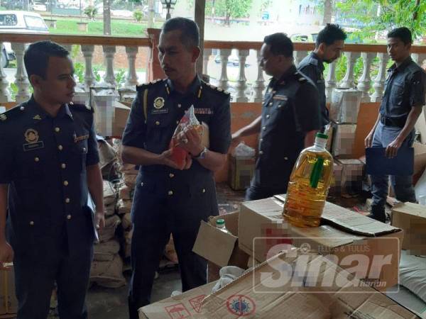 Mohd Sakhri (dua dari kiri) bersama pegawai KPDNHEP Perak melakukan pemeriksaan bekalan minyak masak di sebuah kedai borong di Pengkalan Hulu hari ini.