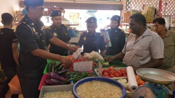 Abdul Mubin (kiri) bersama anggotanya melakukan pemantauan di 35 premis perniagaan di sekitar daerah Raub, Khamis lalu.