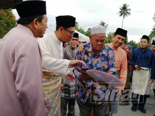 Ahmad Faizal menyampaikan replika kunci rumah kepada seorang daripada 12 penerima Projek Baiti TNB tahun ini.