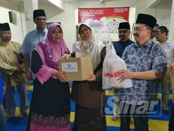 Fuziah menyampaikan sumbangan kepada ibu tunggal dan anak yatim pada program kacau bubur lambuk dan sumbangan Ramadan Flat Pak Mahat di surau flat tersebut, hari ini.