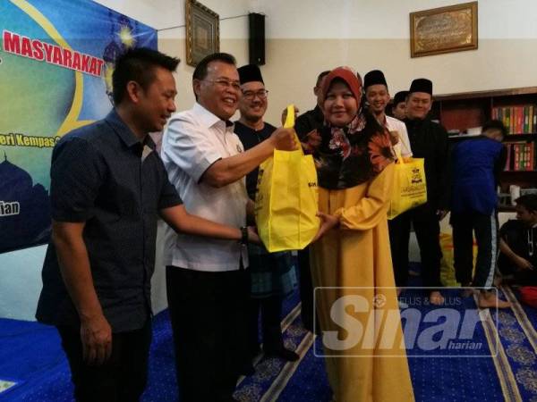 Osman (dua,kiri) menyampaikan sumbangan Majlis Agama Islam Johor (MAIJ) kepada asnaf di kawasannya dalam Program Sehari PKM Bersama Masyarakat di Kg Melayu Sri Kempas 2 di sini hari ini.