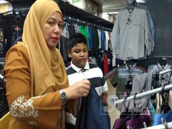 Normah membantu Mohd Firdaus memilih baju raya di Pasar raya Econsave Bercham, di sini. 