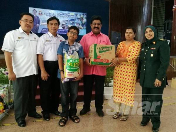 Pelajar Tingkatan 1, Pirreim Vengades (tengah) dan ibunya, Vijaya Maruthan, 42 menerima sumbangan daripada SMK Seri Perling dalam Majlis Penyampaian Prihatin Bersamamu di sini hari ini.