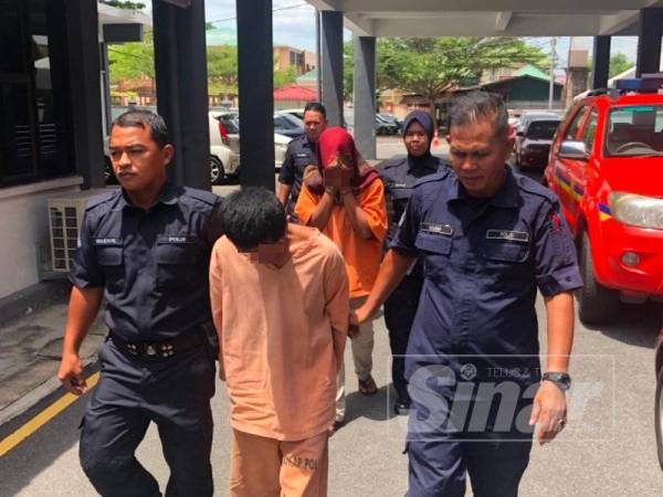 Tertuduh Mohd Hafiz Abdullah, 31, (tengah) dan isterinya, Farah Nasuha Razali, 28, (belakang) dikawal ketat polis keluar dari Mahkamah Sesyen Kota Bharu selepas dihukum atas kesalahan mendera tiga anak mereka.