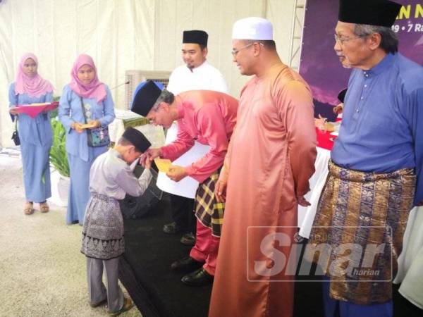 Menteri Kesihatan, Datuk Seri Dr Dzulkefly Ahmad sambil diiringi Amirudin (dua dari kanan) menyampaikan sumbangan kepada salah seorang penerima pada Majlis Iftar Perdana Bersama Pemimpin di Masjid Ar Rahman Kampung Bukit Badong, di sini hari ini.