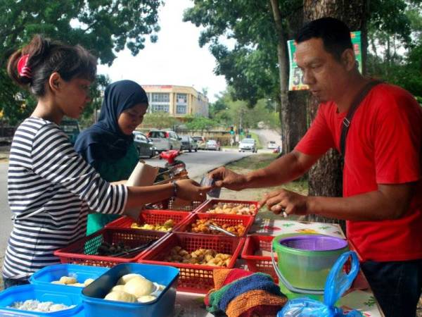 Mohd Hasmi Idris, 39, sedang melayan pelanggan yang membeli cucur 'sekupang' dijualnya sebaik membuka gerai di Jalan Keranji di sini. - FOTO BERNAMA