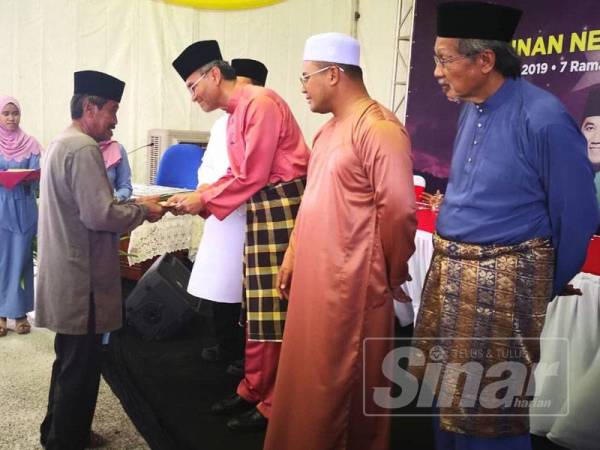 Menteri Kesihatan, Datuk Seri Dr Dzulkefly Ahmad menyampaikan sumbangan kepada penerima sambil diperhatikan Amirudin pada Majlis Iftar Perdana Bersama Pemimpin di Kampung Bukit Badong semalam.