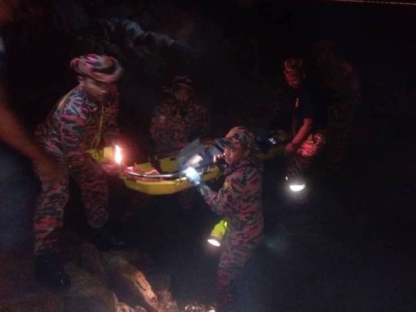 Anggota bomba membawa keluar mayat mangsa yang ditemui di celahan batu selepas dipercayai terjatuh ketika memancing di pantai Teluk Batik, semalam. -Foto Ihsan Bomba