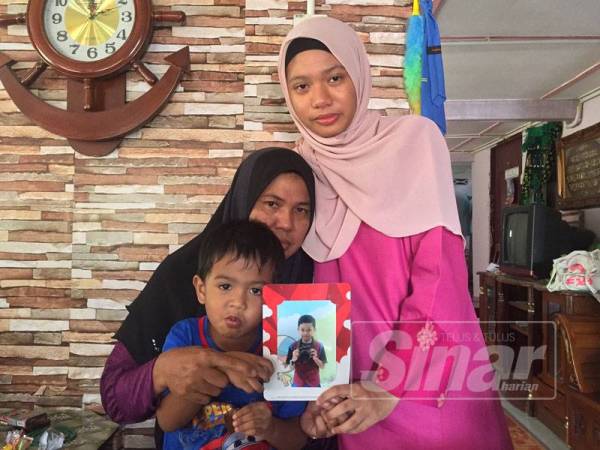 Azizah bersama anak bongsunya Muhammad Aisy dan anak sulungnya Nur Najwa Insyirah menunjukkan gambar Allahyarham Ammar Raziq di kediaman mereka.
