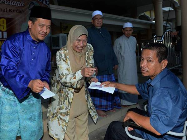 Menteri Perumahan dan Kerajaan Tempatan Zuraida Kamaruddin (dua, kiri) menyampaikan sumbangan kepada Suhaimi Md Isa, 53, yang berkerusi roda pada Majlis Iftar Perdana dan Sumbangan kepada Fakir Miskin di Masjid Batu 5 Taman Ria Mesra 2 Jalan Jeniang, Gurun hari ini. - Foto Bernama