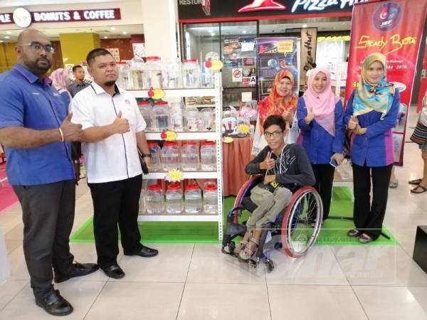 Mohd Faizal (berkerusi roda) sewaktu Program 'Charity Bazaar' di Kluang Mall, Kluang semalam. 