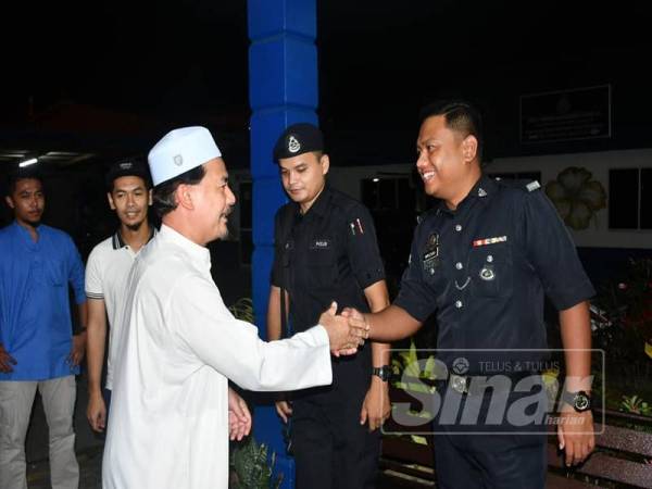 Ahmad Shah (kiri) bersalaman dengan anggota polis dari Balai Polis Chabang Tiga.