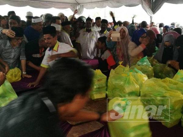 Orang ramai berasak-asak bagi mendapatkan nasi beriani yang disediakan.