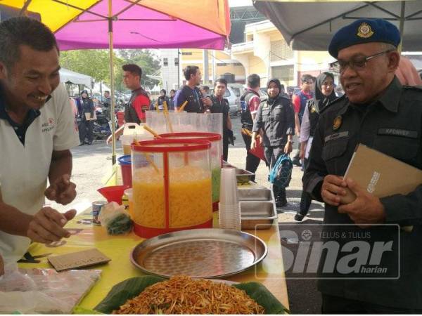 Omar (kanan) berbual dengan peniaga ketika Operasi Bersepadu bersama KPDNHEP Kedah di Bazar Stadium Darul Aman, di sini hari ini.