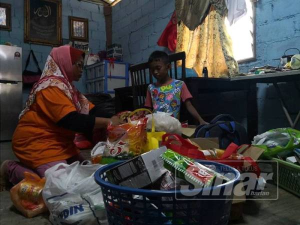 Nor Azila mengemas barang sumbangan orang ramai untuk anak saudaranya.