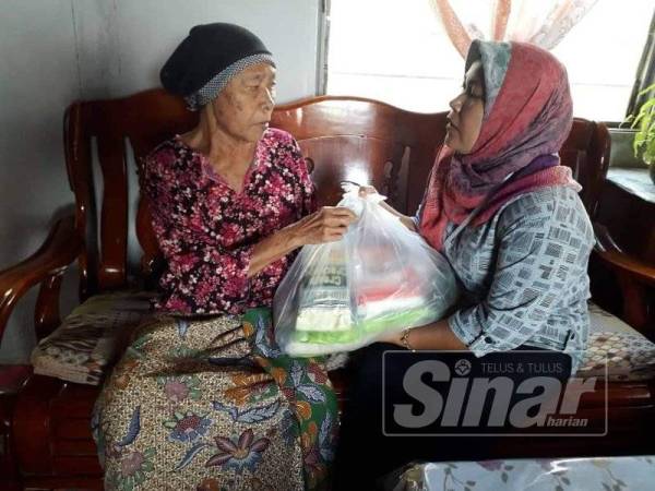 Hasnizawati menyampaikan sumbangan kepada ibu Rokiah di kediaman mereka di Kampung Jalan Perigi semalam.