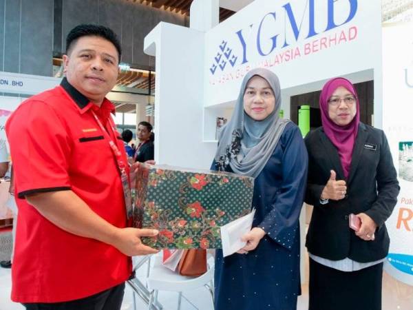 Wan Munadi menyerahkan hadiah kepada guru yang membeli pakej dengan YGMB Travel & Tours.