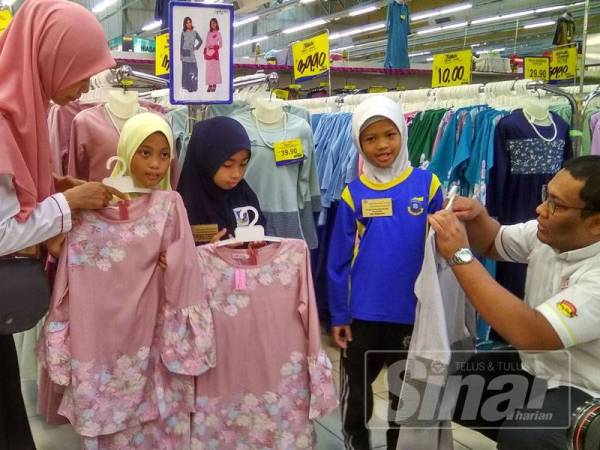 Habibul menunjukkan baju raya kepada salah seorang kanak-kanak yang menyertai program anjuran OK Group di Pasaraya Mydin MITC.