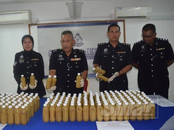 Mohd Said (dua kiri) menunjukkan air ketum botol sejuk beku yang dirampas pada sidang media petang tadi.