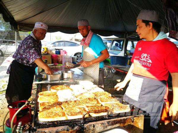 Mohd Razlan (kiri) juga dikenali sebagai Pok Lan sedang menebar serta menggoreng murtabak. 