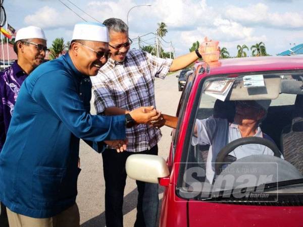 Abd Rahman (kiri) bersama kepimpinannya beramah-mesra bersama penduduk pada Majlis Pemberian Bubur Lambuk di Pekan Bagan Terap di sini.