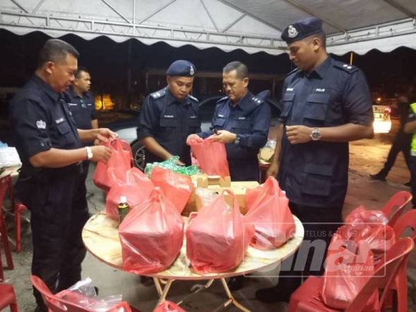 Hasron (dua, kiri) bersama pegawainya memeriksa pek makanan yang akan diedarkan sempena program Kongsi Sahur bersama agensi keselamatan daerah Kampar pagi tadi. 