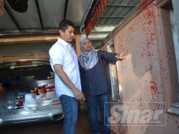 Norhayati menunjukkan kesan cat dibaling ke dinding rumahnya kepada Hilman, dalam kejadian ancaman baru-baru ini.