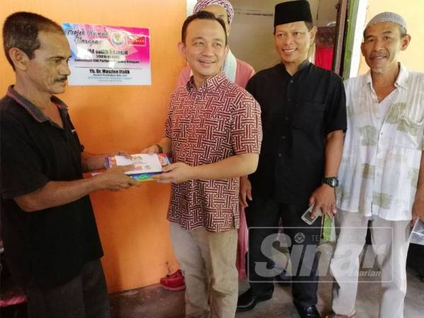 Maszlee (tiga, kanan) menyerahkan sumbangan kepada penerima bantuan di Kampung Parit Haji Hashim, Simpang Renggam. 