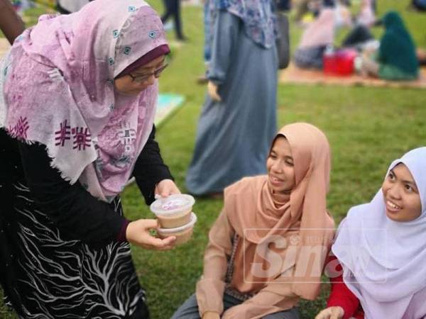 Fuziah mengedarkan bubur lambuk kepada orang ramai di Padang MPK hari ini. 