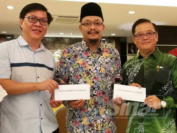 Mohd Kazim menerima sumbangan daripada Chean (kiri) dan Yean Ming pada program berkenaan.