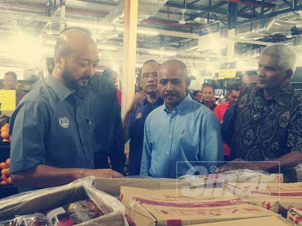 Mukhriz (kiri) meninjau barangan keperluan asas di sebuah pasaraya di Batu 5 Sik yang menggunakan sistem kad KIDA.