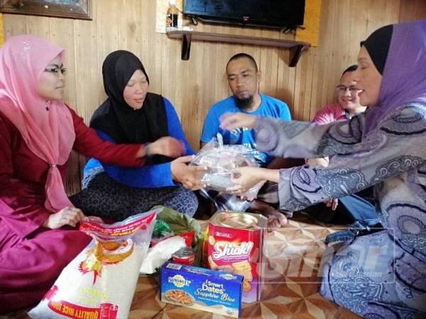 Rosmiza (kiri) bersama Raja Rusmin menyampaikan pek makanan, beras dan wang tunai kepada keluarga Hamizi di Kampung Telaga Lanas semalam.